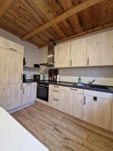 a large kitchen with wooden cabinets and a sink at Ferienwohnung am Eisenberg in Schmiedefeld am Rennsteig