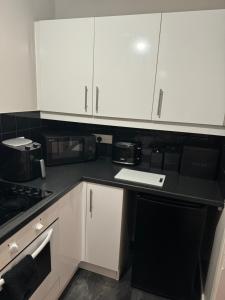 a kitchen with white cabinets and a black counter top at *RARE FIND* 3 story, 2 bedroom house in Coleshill