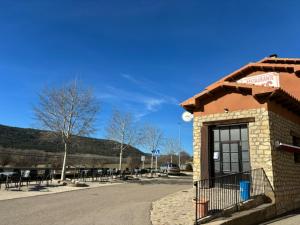 Hotel el Cid في Torres de Albarracín: مبنى به طاولات وكراسي في موقف للسيارات