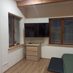 a room with a flat screen tv and two windows at S Neries 19 apartamentai su parkingu in Šiauliai