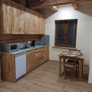 eine Küche mit Holzschränken und einem Tisch mit Mikrowelle in der Unterkunft S Neries 19 apartamentai su parkingu in Šiauliai