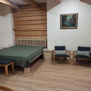 1 Schlafzimmer mit einem grünen Bett und 2 Stühlen in der Unterkunft S Neries 19 apartamentai su parkingu in Šiauliai