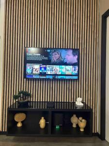 a flat screen tv on a wall with vases at Escapade Cinéma : Duplex 50m² in Linas