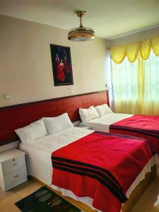 a bedroom with two beds with red and white sheets at hongyuanprimierhotel in Accra
