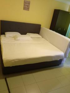 a bed with white sheets and pillows in a room at FAMILY HOTEL in Kuala Kubu Baharu