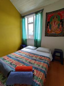 a bedroom with a bed and a window with a blanket at ZIPA HOSTEL in Zipaquirá