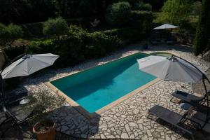 a swimming pool with two umbrellas and two chairs at Gîte Le Bel Endroit in Saint-André-de-Cruzières