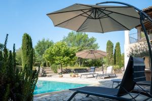 Saint-André-de-Cruzières的住宿－Gîte Le Bel Endroit，一个带遮阳伞和椅子的庭院和一个游泳池