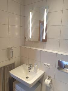 un bagno bianco con lavandino e specchio di Landhaus Bad Rotenfels - Bethel a Gaggenau Altre 18 foto