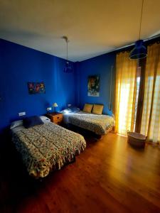 1 dormitorio con 2 camas y pared azul en Casa Cotis Beceite, en Beceite