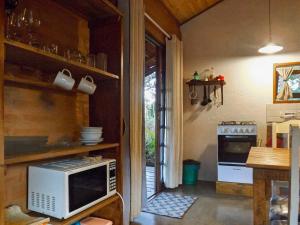 una cucina con forno a microonde e piano cottura di Chalé rústico na natureza de SFX a São Francisco Xavier