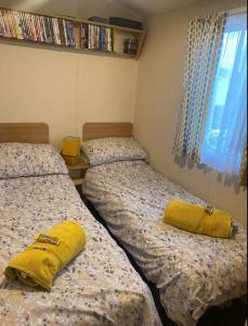 two beds in a bedroom with yellow pillows on them at LottieLou’s Hot Tub breaks at Tattershall Lakes in Lincoln