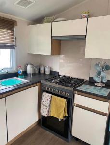 a kitchen with white cabinets and a stove top oven at LottieLou’s Hot Tub breaks at Tattershall Lakes in Lincoln