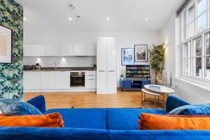 a living room with a blue couch and a kitchen at Stylish 1 Bedroom Apartment Near Heathrow, Windsor Castle, Thorpe Park - Staines London TW18 in London