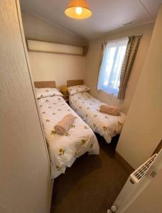 two beds in a small room with a window at LottieLou’s Hot Tub breaks at Tattershall Lakes in Lincoln