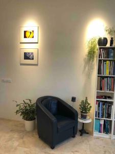 a black chair in a living room with a book shelf at Prachtig guesthouse aan het water in Almere