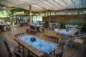 a restaurant with wooden tables and chairs and tablesearcher at Hotel Canto do Rio Maresias in Maresias