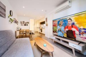 2 BD Luxury apartment at heart of Docklands with 85" flat TV & Free Carpark في ملبورن: غرفة معيشة مع تلفزيون بشاشة مسطحة كبيرة