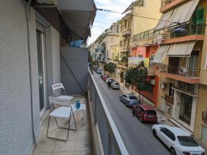 Lavender-Emma cosy apartment near city center في أثينا: بلكونه فيها كرسي وشارع فيه سيارات