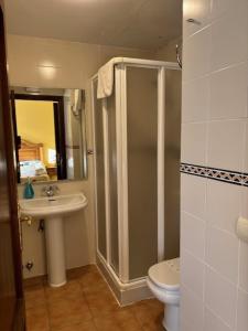 y baño con ducha, aseo y lavamanos. en Hotel el Cid, en Torres de Albarracín