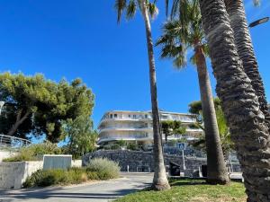 Luxury Apartment with amazing SEA view at Cap d'Antibes في أنتيب: مجموعة من أشجار النخيل أمام مبنى