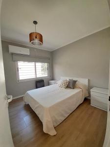 Un dormitorio con una gran cama blanca y una ventana. en Los Robles, en Mercedes