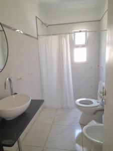 Un baño con lavabo, inodoro y ventana. en Los Robles, en Mercedes