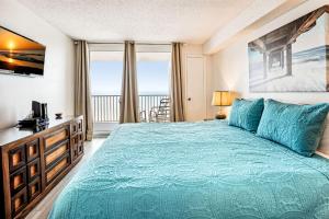 a bedroom with a blue bed with a view of the ocean at Sand Castle 2901 in Clearwater Beach