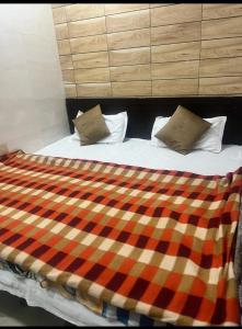 een bed met een geruite deken en 2 kussens bij Arora guest house in Amritsar