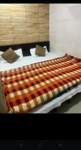 een groot bed met een geruite deken erop bij Arora guest house in Amritsar