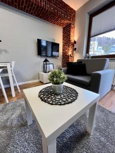 a living room with a white table and a couch at Apartament DOMINO Krynica Zdrój in Krynica Zdrój