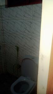 a bathroom with a toilet and a white tiled wall at Jayanika home stay in Tangalle