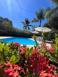 a swimming pool with flowers in front of a house at Chalés Praias do Sul in Porto De Galinhas