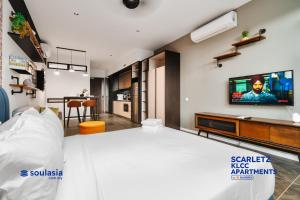 Scarletz KLCC Apartments by soulasia في كوالالمبور: غرفة نوم مع سرير وتلفزيون على الحائط