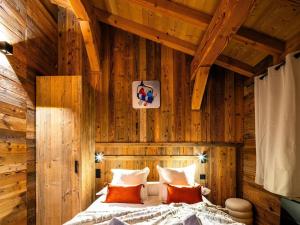 a bedroom with wooden walls and a bed with orange pillows at Chalet haut de gamme Bolquère * L'échappée Belle * in Bolquere Pyrenees 2000