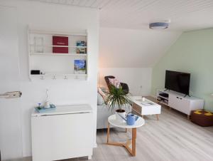 uma sala de estar branca com uma mesa e uma televisão em FeWo Nordlicht em Hage
