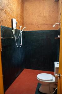 a bathroom with a toilet and a hose on the wall at Hotel Hideaway Garage in Dambulla
