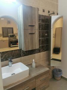 a bathroom with a white sink and a mirror at منزل مريح بحديقة ومسبح خاص in Abyār ‘Alī