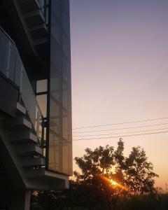 a building with the sun setting behind a tree at Padmaa Hampi Echo Villa in Hampi