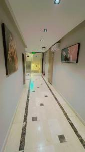 un pasillo largo con suelo de baldosa y pinturas en las paredes en السعادة سويت - الملز الرياض Saada Suites Serviced Apartments en Riad