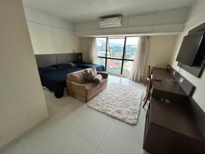 um quarto com uma cama, um sofá e uma janela em Tropical Executive Flat Vista Incrível para a Orla em Manaus