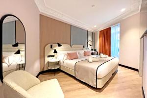 a bedroom with a large bed and a chair at Soho Boutique Turia in Valencia
