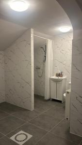 a white bathroom with a sink and a shower at Marzebilla pod Klínovcem in Chomutov