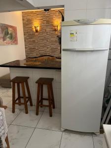 einen weißen Kühlschrank in einer Küche mit einem Tisch in der Unterkunft Apartamento na Praia de Itararé in São Vicente