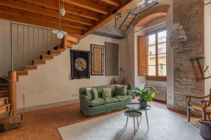 a living room with a green couch and a staircase at Old Bridge large and unique artful apartment with elevator in Florence