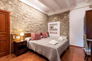 a bedroom with a bed and a stone wall at Hostal Can Xicu in Capmany