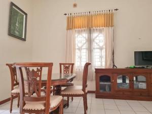 Homestay Pesona Sintuk Bontang A9 في Bontang: غرفة طعام مع طاولة وكراسي وتلفزيون