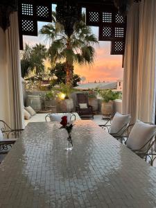 una mesa con un jarrón con una rosa. en Riad des Fragrances dar el Bacha en Marrakech
