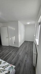 a white room with a bed and a wooden floor at Entire 2 Bedroom Apartment in Oldbury