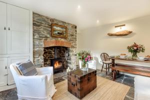 a living room with a stone fireplace and a piano at Cottage in Tranquil Hamlet in Salcombe